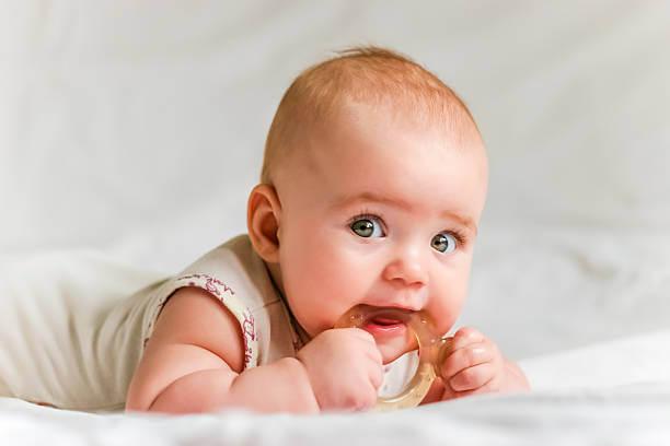 a baby lying on its stomach and holding a toy in its mouth