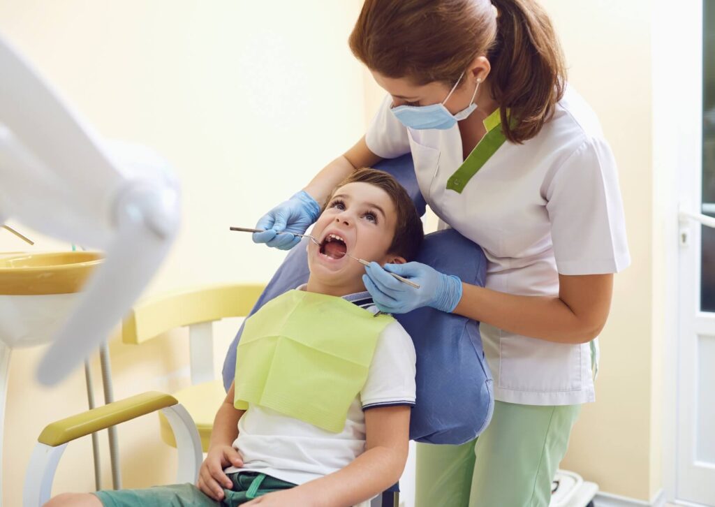 Pediatric dentist examining a child's teeth before applying dental sealants to help prevent cavities.
