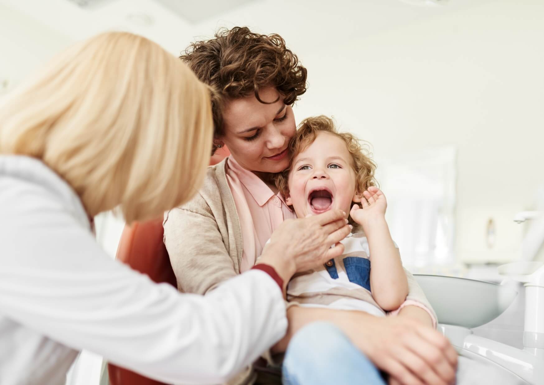 Parent comforting a young child during a first dental visit to help prepare them for a positive dental experience.