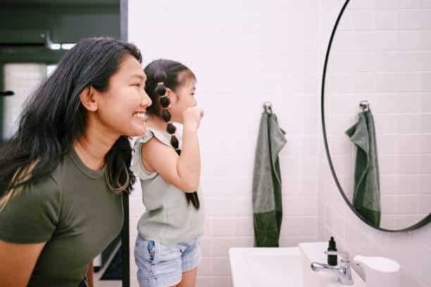 photo showing a mother teaching her kid how to brush her teeth