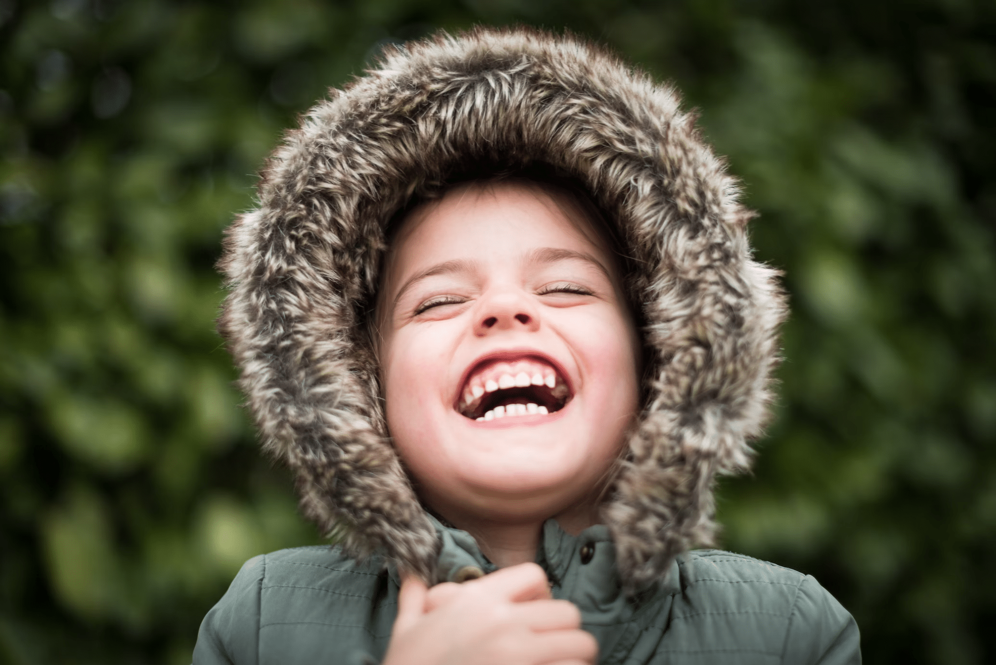 a little kid in a hoodie jacket smiling widely
