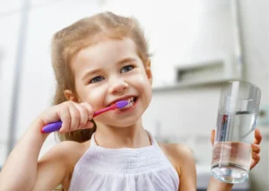 Young child brushing her teeth to help prevent cavities and maintain good oral hygiene.