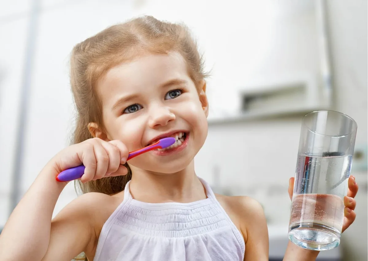 Young child brushing her teeth to help prevent cavities and maintain good oral hygiene.