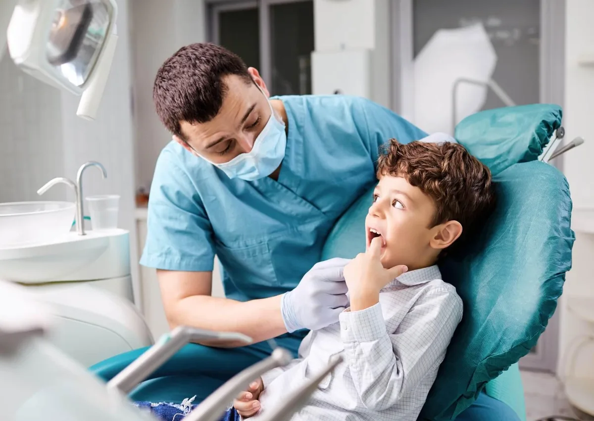Pediatric dentist examining a young boy’s teeth during a routine dental visit.